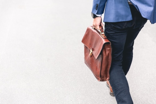 Person walking with brown leather bag