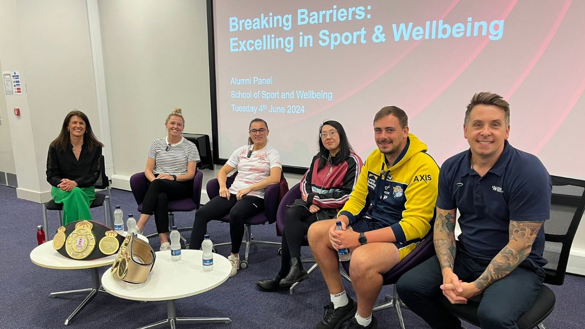 Four women and two men sit in front of a board displaying the words Breaking Barriers