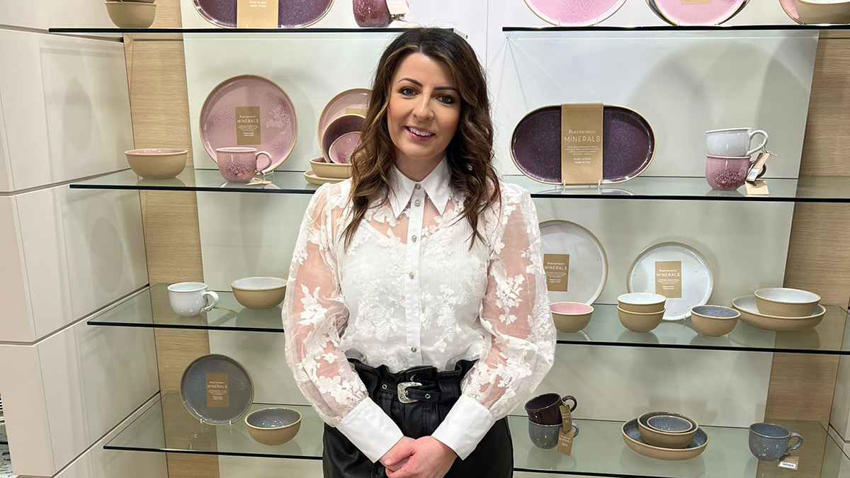 A young professional in a white lacy shirt smiling at work.