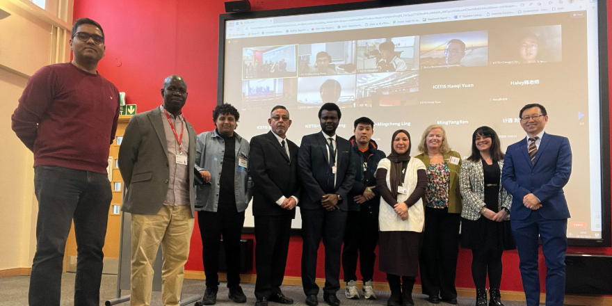 Event attendees stand in front of display screen