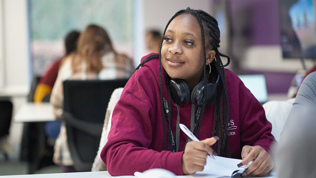 A student in a burgundy hoodie paying attention in classroom.