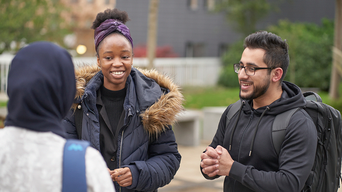 Three students chatting on campus.
