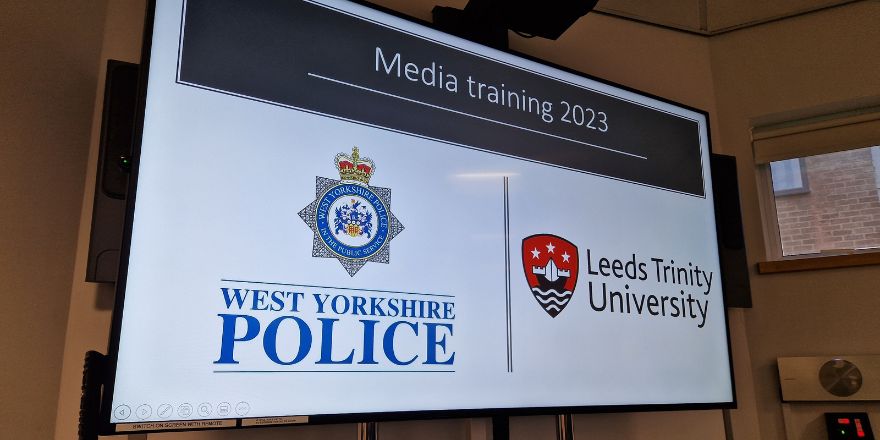 A board displays the logos of the West Yorkshire Police and Leeds Trinity University