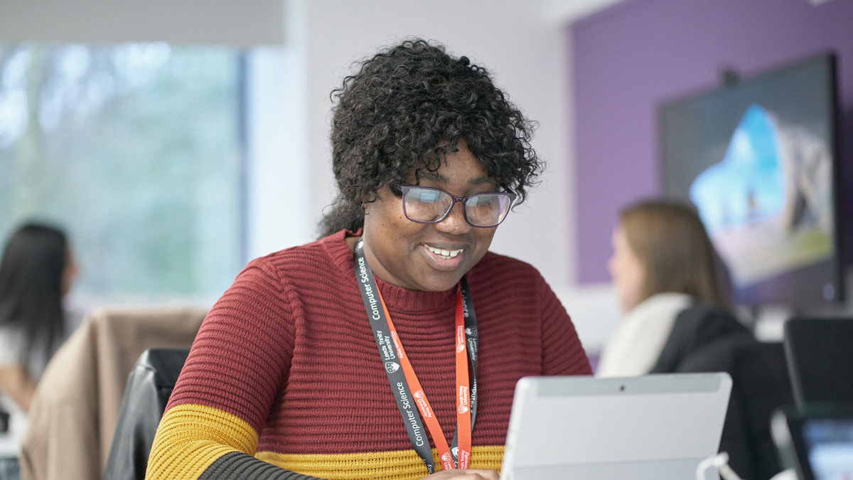 A student smiling and working on a laptop.