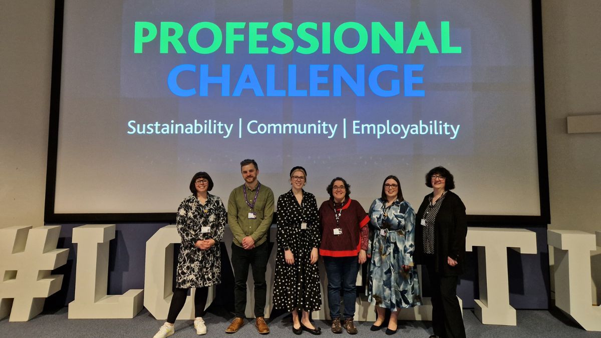 Six members of staff stand in front of a screen displaying the words Professional Challenge