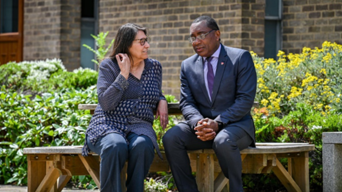 Man and woman both in blue sat on bench talking