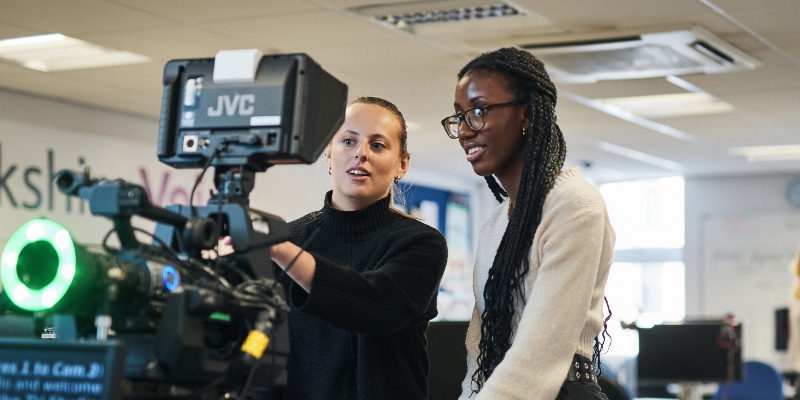 Two female journalism students setting up a camera and autocue