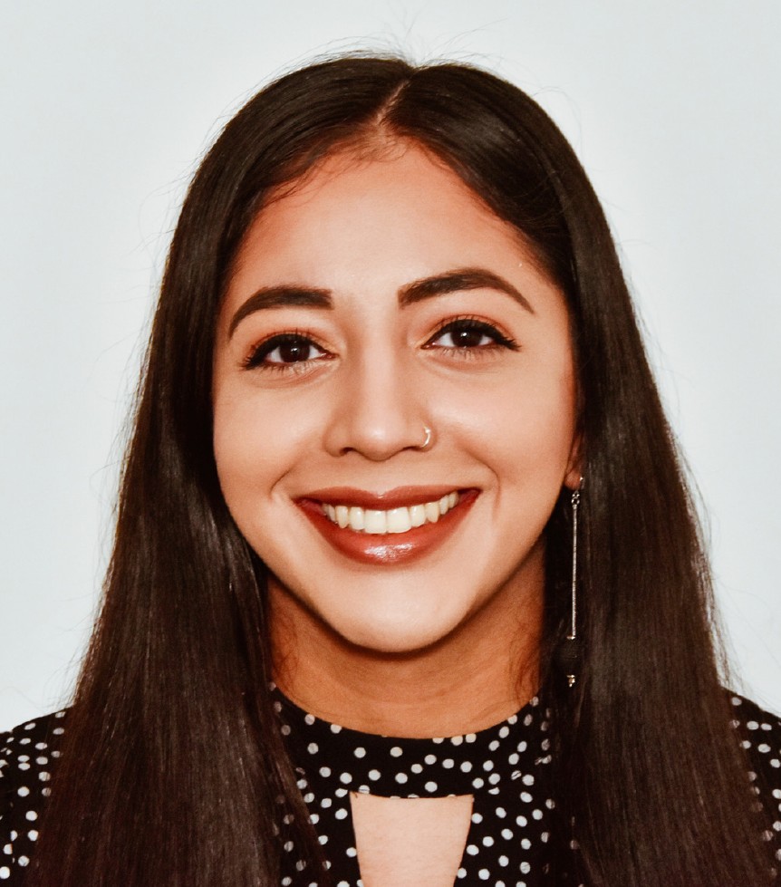 Headshot of smiling woman wearing nose ring, ear ring and spotty top.